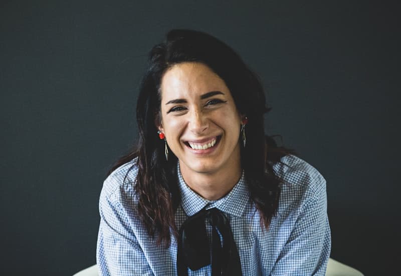 A smiling professional in a checked shirt against a dark background